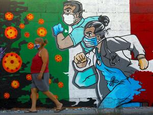 A woman walks past a coronavirus-related mural painted by artist Mick Martinez in Ciudad Juarez, state of Chihuahua, Mexico, on May 19, 2020. HERIKA MARTINEZ / AFP
