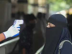 A railway official checks the temperature of a woman queueing to enter the Kamalapur railway station after the government-imposed lockdown as a preventive measure against the COVID-19 coronavirus ended, in Dhaka on May 31, 2020. Munir UZ ZAMAN / AFP