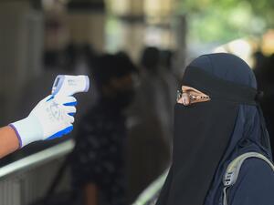 A railway official checks the temperature of a woman queueing to enter the Kamalapur railway station after the government-imposed lockdown as a preventive measure against the COVID-19 coronavirus ended, in Dhaka on May 31, 2020. Munir UZ ZAMAN / AFP