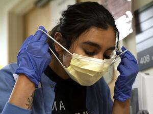 Charge nurse Liliana Palacios carefully removes her mask and PPE after tending to a patient with COVID-19 in the acute care COVID unit at Harborview Medical Center on May 7, 2020 in Seattle, Washington. (AFP)