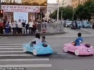 Social media footage captured the parent and her friend driving two play cars carrying the young boy on a crossroad with heavy traffic as pedestrians looked on. (Video Screenshot)