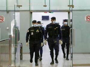 Kuwaiti policemen wearing protective masks wait at Sheikh Saad Airport in Kuwait City, on February 22, 2020, before transferring Kuwaitis arriving from Iran to a hospital to be tested for coronavirus. (AFP)