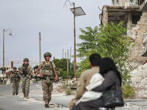 Turkish soldiers patrol along a road past destroyed buildings atop the Arbaeen hill overlooking Ariha in the southern countryside of Syria's Idlib province on May 26, 2020. OMAR HAJ KADOUR / AFP