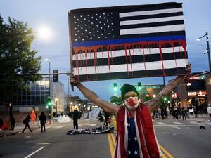 A demonstrator holds up a sign during a protest in Denver, Colorado, on May 31, 2020, over the death of George Floyd, an unarmed black man who died while while being arrested and pinned to the ground by the knee of a Minneapolis police officer. Thousands of National Guard troops patrolled major US cities after five consecutive nights of protests over racism and police brutality that boiled over into arson and looting, sending shock waves through the country. The death Monday of an unarmed black man, George 