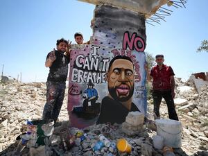Syrian artists Aziz Asmar and Anis Hamdoun finish a mural depicting George Floyd, an unarmed African-American man who died while while being arrested and pinned to the ground by the knee of a Minneapolis police officer, in the town of Binnish in Syria's northwestern Idlib province on June 1, 2020. OMAR HAJ KADOUR / AFP