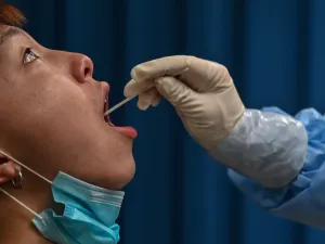 This file photo taken on May 14, 2020 shows a medical worker taking a swab sample from a man to be tested for the COVID-19 coronavirus in Wuhan in China’s central Hubei province. Chinese authorities have completed a mass coronavirus testing campaign in Wuhan, finding only 300 positive results among nearly 10 million people in the city where the pandemic began, local officials said on June 2, 2020. Hector RETAMAL / AFP