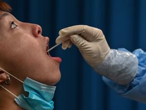 This file photo taken on May 14, 2020 shows a medical worker taking a swab sample from a man to be tested for the COVID-19 coronavirus in Wuhan in China’s central Hubei province. Chinese authorities have completed a mass coronavirus testing campaign in Wuhan, finding only 300 positive results among nearly 10 million people in the city where the pandemic began, local officials said on June 2, 2020. Hector RETAMAL / AFP
