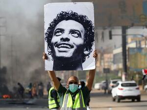 A mask-clad man holds a picture of a Abdulsalam Kisha, a Sudanese protester who was killed in a raid on an anti-government sit-in in 2019, during a protest in the Riyadh district in the east of the capital Khartoum on the anniversary of the raid on June 3, 2020. One year after the 25-year-old Abdulsalam's killing in the dispersal of Sudan's main protest camp, his father Kisha is still holding out hope that the killers be brought to justice as he calls for an international probe. The young protester was kill