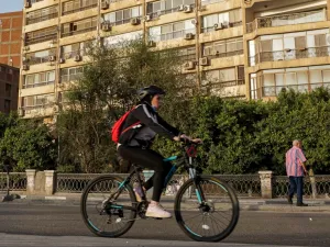 A woman cycles while wearing a face mask around her neck along the Nile riverfront in the Egyptian capital Cairo's southern district of Maadi on May 22, 2020, during the COVID-19 coronavirus pandemic. Khaled DESOUKI / AFP