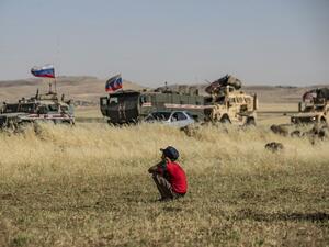 A Syrian boy looks at Russian and US military vehicles in the northeastern Syrian town of al-Malikiyah (Derik) at the border with Turkey, on June 3, 2020. DELIL SOULEIMAN / AFP