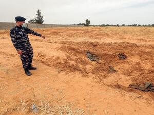 A member of security forces affiliated with the Libyan Government of National Accord (GNA)'s Interior Ministry points at the reported site of a mass grave in the town of Tarhuna, about 65 kilometres southeast of the capital Tripoli on June 11, 2020. Mahmud TURKIA / AFP