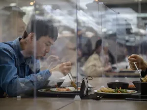 In this file photo taken on April 9, 2020 employees sit behind protective screens as part of preventative measures against the COVID-19 novel coronavirus, as they eat in a cafeteria at the offices of Hyundai Card credit card company in Seoul. Ed JONES / AFP