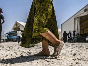 In this file photograph taken on July 22, 2019, a young child walks barefoot at al-Hol camp for displaced people, in al-Hasakeh governorate, north-eastern Syria, as people collect UN-provided humanitarian aid packages. The government said June 22, 2020, that it had brought home 10 French children of jihadist fighters overnight from a refugee camp in Syria, the latest in a piecemeal repatriation process since the Islamic State group was ousted from its Syrian base in March 2019. Delil souleiman / AFP