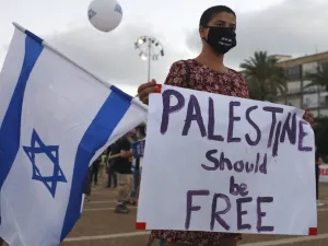 A protester, wearing a protective mask due to the COVID-19 pandemic, holds placards during a demonstration in Tel Aviv's Rabin Square to denounce Israel's plan to annex parts of the occupied West Bank, on June 23, 2020. Only a week before Prime Minister Benjamin Netanyahu intends to kick-start annexation plans in the occupied West Bank, Israel's premier is facing challenges at home and abroad. JACK GUEZ / AFP