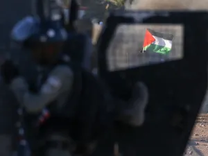 The Palestinian national flag is seen through the window of an Israeli military vehicle amid clashes following a rally against Israel's West Bank annexation plans, in the Jordan Valley village of Fasayil on June 24, 2020. JAAFAR ASHTIYEH / AFP