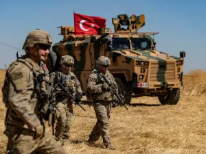 US troops walk past a Turkish military vehicle on the outskirts of Tal Abyad town along the Syrian-Turkish border on 8 September (AFP)