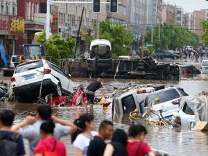 Residents look towards submerged cars in a flooded street in Yongji, a county under the administration of the city of Jilin in northeast China's Jilin province on July 14, 2017. Photo: STR/AFP