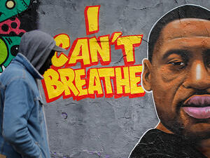 A man walks past a graffiti on a wall depicting a portrait of George Floyd, a black man who died in Minneapolis after a white policeman kneeled on his neck for several minutes, at Mauer Park in Berlin's Prenzlauer Berg district on May 30, 2020. (Photo by David GANNON / AFP)