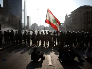 Lebanese protesters wave the national flag in front of riot police in Beirut /AFP