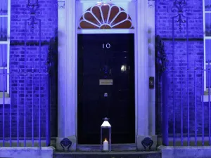 A candle is lit and placed on the doorstep of 10 Downing Street in central London on July 4, 2020 in honour of the tens of thousands of people who have died as a result of the coronavirus pandemic in the UK as the building itself is lit up blue as a tribute to NHS workers and to mark the 72nd anniversary of the NHS. Tolga AKMEN / AFP