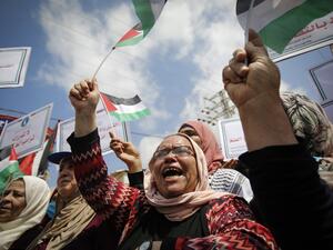 Palestinian women lift national flags and placards during a rally for supporters of the Fateh movement against Israel's West Bank annexation plans, in Beit Hanun in the north of the Gaza Strip, on July 6, 2020. MOHAMMED ABED / AFP