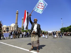 A Yemeni gunman loyal to the Huthi movement lifts flags during a rally in the capital Sanaa, to show support to the movement against the Saudi-led intervention in the country on July, 7, 2020. Mohammed HUWAIS / AFP