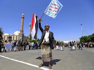 A Yemeni gunman loyal to the Huthi movement lifts flags during a rally in the capital Sanaa, to show support to the movement against the Saudi-led intervention in the country on July, 7, 2020. Mohammed HUWAIS / AFP