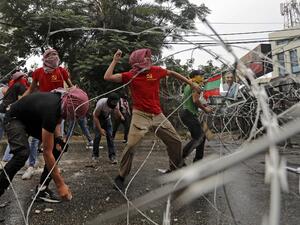 Protesters wearing shirts bearing the logo of the Marxist-Leninist Popular Democratic Party (red) and others wearing bandanas showing the logo of the Shiite movement Hezbollah (yellow) throw stones amidst clashes with security forces during an anti-US demonstration near the United States' Embassy headquarters in Awkar, northeast of Lebanon's capital Beirut on July 10, 2020. JOSEPH EID / AFP