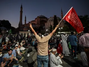A man flashes the V for Victory hand sign and waves a flag outside the Hagia Sophia museum in Istanbul on July 10, 2020 as people gather to celebrate after a top Turkish court revoked the sixth-century Hagia Sophia's status as a museum, clearing the way for it to be turned back into a mosque. Ozan KOSE / AFP