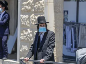 An Ultra-Orthodox Jewish man, wearing a protective face mask, stands at a checkpoint erected to block entrance to the neighbourhoods of Romema and Kiryat Belz after authorities imposed a lockdown to combat the spread of the Coronavirus, in Jerusalem on July 12, 2020. AHMAD GHARABLI / AFP