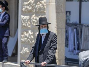 An Ultra-Orthodox Jewish man, wearing a protective face mask, stands at a checkpoint erected to block entrance to the neighbourhoods of Romema and Kiryat Belz after authorities imposed a lockdown to combat the spread of the Coronavirus, in Jerusalem on July 12, 2020. AHMAD GHARABLI / AFP