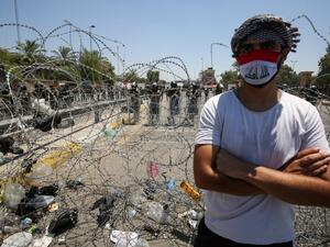 An Iraqi man stands in front of security forces during a protest outside the Green Zone in the capital Baghdad on July 12, 2020 to demand a curb on paramilitary groups and restricting the use of weapons to government security forces. AHMAD AL-RUBAYE / AFP