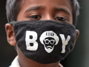 A boy wearing a facemask as a preventive measure against the spread of the COVID-19 coronavirus, looks on near a paddy field in Medak district of Telangana state on July 15, 2020. India joins a raft of countries and cities across the globe to reimpose localised lockdowns and other restrictions in the face of new outbreaks of the disease. Noah SEELAM / AFP
