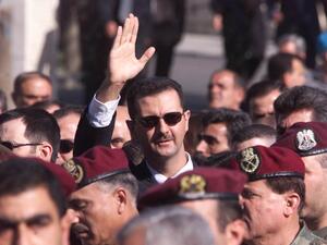 A file photo taken on June 13, 2000 shows Syrian heir apparent Bashar al-Assad waving to supporters as he marches behind the coffin of his father, Syrian President Hafez al-Assad, during his funeral in Damascus. Bashar al-Assad's rise to power after three decades of his father's iron-fisted rule raised hope of democratic opening. But 20 years later, Syria is isolated and war-ravaged. Crumbling under a stinging economic downturn, Western sanctions and nine years of war, Syria today is a far cry from the visi