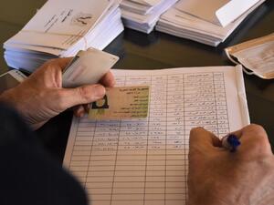 A voting official registers a woman to vote at a polling station in the Nubl neighbourhood of Aleppo on July 19, 2020, during the parliamentary elections. Syrians vote today to elect a new parliament as the Damascus government grapples with international sanctions and a crumbling economy after retaking large parts of the war-torn country. AFP 