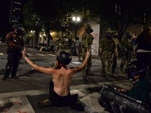 A topless protestor (C) gestures in front of federal police personnel in Portland, Oregon early July 26, 2020, as protests continue across the United States following the death in Minneapolis of unarmed African-American George Floyd. (AFP/File)