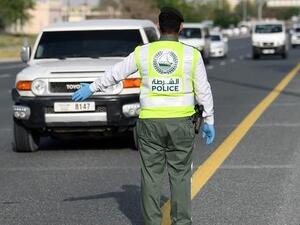 A policeman stops vehicles at a security checkpoint to examine passengers for exit permits in Dubai on April 9. (AFP)