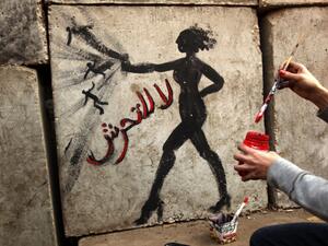 An Egyptian activist draws graffiti depicting a woman and reading in Arabic: “No to Sexual Harassment” on a wall outside the presidential palace in Cairo on December 14, 2012. Photo: PATRICK BAZ / AFP
