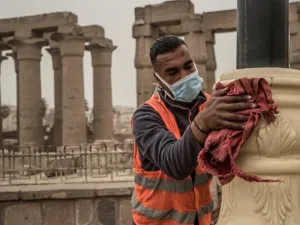 A municipality worker cleans lamp posts amid coronavirus fears outside the Luxor Temple, March 12, 2020. (AFP)