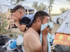 Man and boy cry after police fire tear gas during clashes at Moira refugee camp on the Greek island of Lesbos on Sunday (AFP)