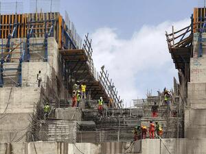 Construction workers stand next to a big rock wall at the Grand Ethiopian Renaissance Dam (GERD), near Guba in Ethiopia. AFP
