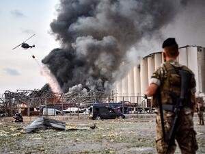 Lebanese army soldiers stand while behind a helicopter puts out a fire at the scene of an explosion at the port of Lebanon's capital Beirut on August 4, 2020. STR / AFP
