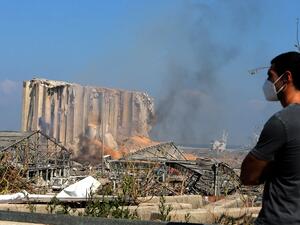 A man wearing a protective mask against the coronavirus stands across the road from the damaged grain silos of Beirut's harbour August 5, 2020, one day after a powerful twin explosion tore through Lebanon's capital, resulting from the ignition of a huge depot of ammonium nitrate at the city's main port. Rescuers searched for survivors in Beirut after a cataclysmic explosion at the port sowed devastation across entire neighbourhoods, killing more than 100 people, wounding thousands and plunging Lebanon deepe