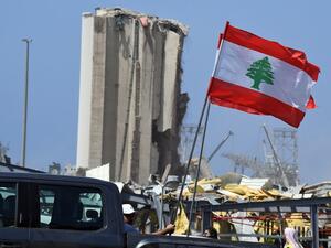 Lebanese people carry the national flag as they drive past the blast site in the capital Beirut on August 8, 2020, four days after a monster explosion killed more than 150 people and disfigured the Lebanese capital. A fire at Beirut port on August 4 ignited a stock of ammonium nitrate and triggered an explosion that was felt in neighbouring countries and destroyed entire neighbourhoods of the city. AFP