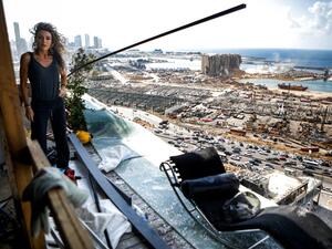 Karina Sukkar, a Lebanese architect and designer, stands the balcony of her damaged apartment overlooking the ravaged port of Lebanon's capital Beirut, in the neighbourhood of Mar Mikhael on August 9, 2020, in the aftermath of a colossal explosion that occurred days prior due to a huge pile of ammonium nitrate that had languished for years at a port warehouse. The huge chemical explosion that hit Beirut's port, devastating large parts of the Lebanese capital and claiming over 150 lives, left a 43-metre (141