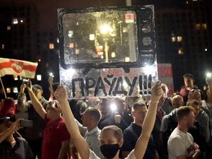 A Belarus opposition supporter holds a fiberglass sheet with a drawn TV and an inscription reading "The truth!!!" near the State TV and radio company during a protest rally against police violence recent rallies of opposition supporters, who accuse strongman Alexander Lukashenko of falsifying the polls in the presidential election, in central Minsk, late on August 15, 2020. Sergei GAPON / AFP