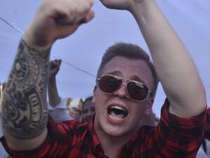 A Belarus opposition supporter shouts as he holds a giant former white-red-white flag of Belarus used in opposition to the government, during a demonstration in central Minsk on August 16, 2020. The Belarusian strongman, who has ruled his ex-Soviet country with an iron grip since 1994, is under increasing pressure from the streets and abroad over his claim to have won re-election on August 9, with 80 percent of the vote. Sergei GAPON / AFP