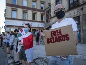 Belarus citizens in Poland hold banners and historical belarusian flags as they stand in a human chain to show solidarity with protesters in Minsk, in Warsaw on August 16, 2020. Wojtek RADWANSKI / AFP