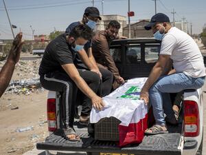 Mourners sit in the back of a vehicle by the Iraqi-flag draped coffin of slain activist Riham Yaaqub during her funeral in the centre of Iraq's southern city of Basra on August 20, 2020. Hussein FALEH / AFP