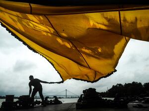 Muslims dry a traditional triangular flag for the upcoming Islamic festival 'Muharram' standing on an empty jetty near the Ganges river as the ferry service has been suspended during the first day of the two-day state-imposed lockdown as a preventive measure against the surge in COVID-19 coronavirus cases, in Kolkata on August 20, 2020. Dibyangshu SARKAR / AFP